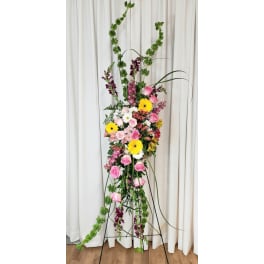 Tall floral standing arrangement with pink and yellow blooms on a black stand