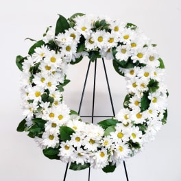 White daisy wreath with yellow centers on a black stand