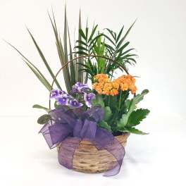 Basket arrangement with purple and orange flowers and a large purple ribbon
