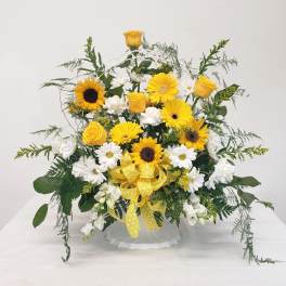 Yellow roses and sunflowers with white daisies in a white basket