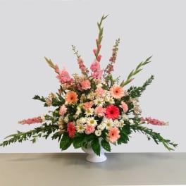 Pink and white mixed flower arrangement in a white pedestal vase
