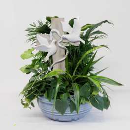 Potted green plant arrangement with a wooden cross and white doves