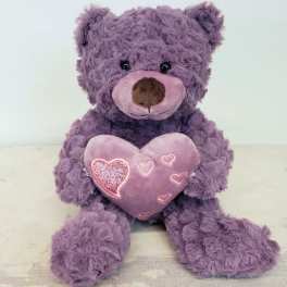 Purple teddy bear holding a pink heart pillow
