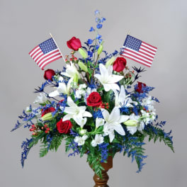 Red roses and white lilies arranged with two American flags in a vase