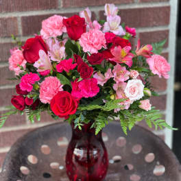 Bouquet of red and pink flowers in a red glass vase