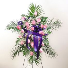Standing spray of pink roses with purple ribbon and palm fronds