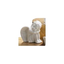 White angel figurine sitting on a wooden surface