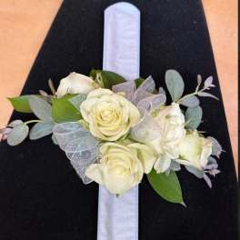 White rose corsage on a black ribbon with silver accents