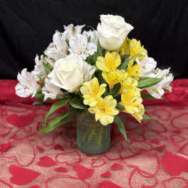 White roses and yellow alstroemeria in a small glass vase