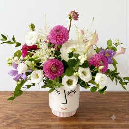 Mixed bouquet in a face-painted ceramic vase with pink, white, and purple blooms