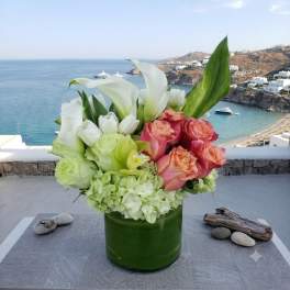 Bouquet of white calla lilies, roses, and pale green hydrangeas in a green vase