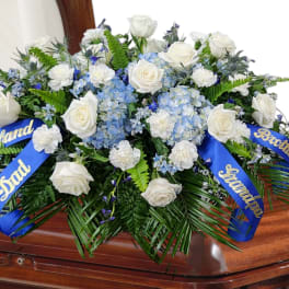 White rose and blue hydrangea casket spray with blue ribbons