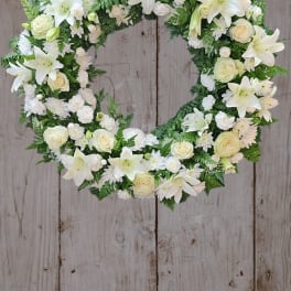 White floral wreath with lilies and roses on a wooden background