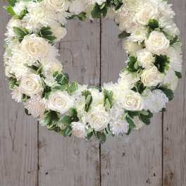 White floral wreath with roses and chrysanthemums on a wooden background