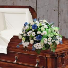 White and blue floral spray on a wooden casket