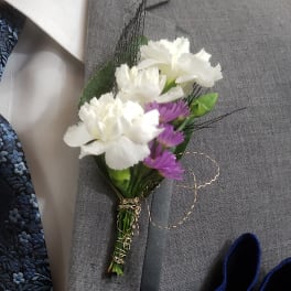 Small white and purple boutonniere pinned to a gray suit jacket