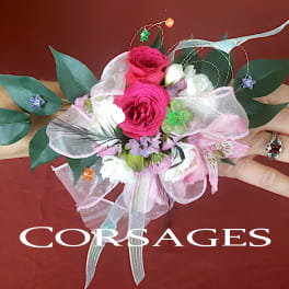 Pink and white floral corsage with ribbon and greenery