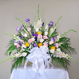 Large floral arrangement with white, pink, purple, and yellow blooms in a white container