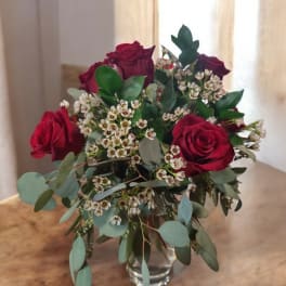 Red roses and white filler flowers in a clear glass vase