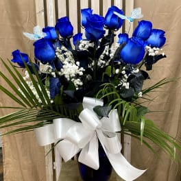 Blue roses in a vase with white baby's breath and a white ribbon