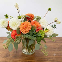Orange and white flower arrangement in a clear glass vase