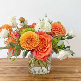 Orange and white flower arrangement in a clear glass vase