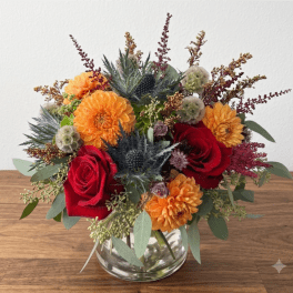 Bouquet of red roses and orange dahlias in a clear glass vase