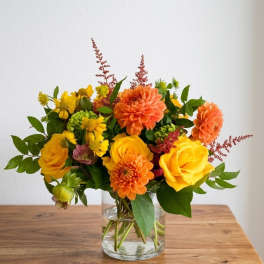 Yellow and orange flowers arranged in a clear glass vase