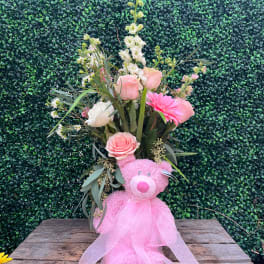 Pink teddy bear with a floral bouquet and sheer ribbon