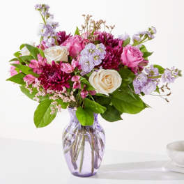 Pink and white mixed bouquet in a purple glass vase