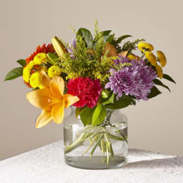 Mixed bouquet of lilies, chrysanthemums, and carnations in a glass vase