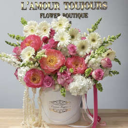 Pink and white flower arrangement in a white hat box with ribbons