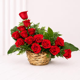 Basket arrangement of red roses with greenery
