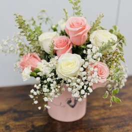 Pink and white roses arranged in a pink box with baby's breath