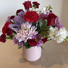 Bouquet of red, pink, and purple flowers in a white vase