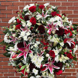 Large standing floral wreath with red, white, and pink blooms on an easel