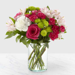 Bouquet of pink, white, and green flowers in a clear glass vase