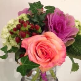 Small arrangement with a peach rose, green hydrangea, and purple ornamental cabbage in a glass vase