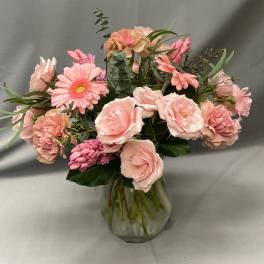 Pink flower arrangement with roses and gerbera daisies in a clear glass vase