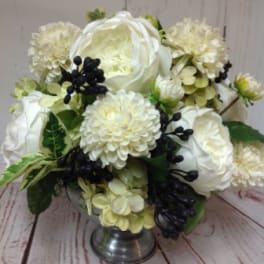 Low arrangement of white roses and mums with dark berries in a silver pedestal bowl