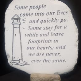 Decorative stone plaque with a lighthouse and memorial quote