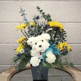 White flower arrangement shaped like a teddy bear with yellow blooms and a blue ribbon