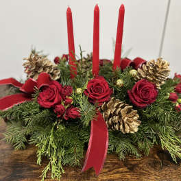 Holiday centerpiece with red candles, red roses, and gold pinecones