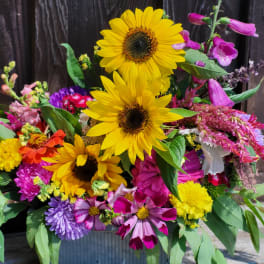 Mixed bouquet with sunflowers and colorful blooms in a metal container