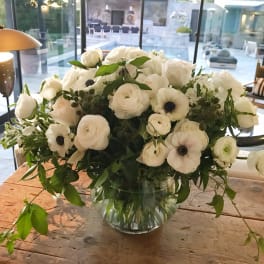 White floral arrangement in a clear glass vase on a wooden table