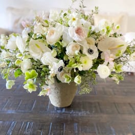 White floral arrangement in a beige vase with anemones and roses