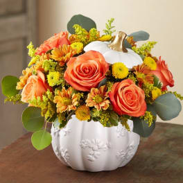 Orange roses and yellow mums arranged in a white pumpkin vase