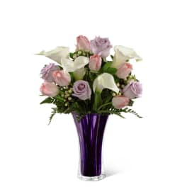 Pink and lavender roses with white calla lilies in a purple vase