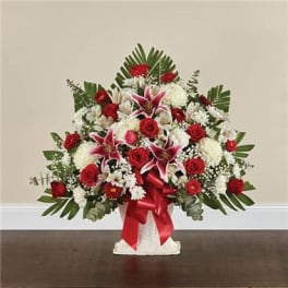Red roses and white lilies in a white vase with a red ribbon