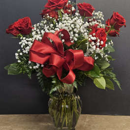 Red roses with baby's breath in a glass vase and red ribbon